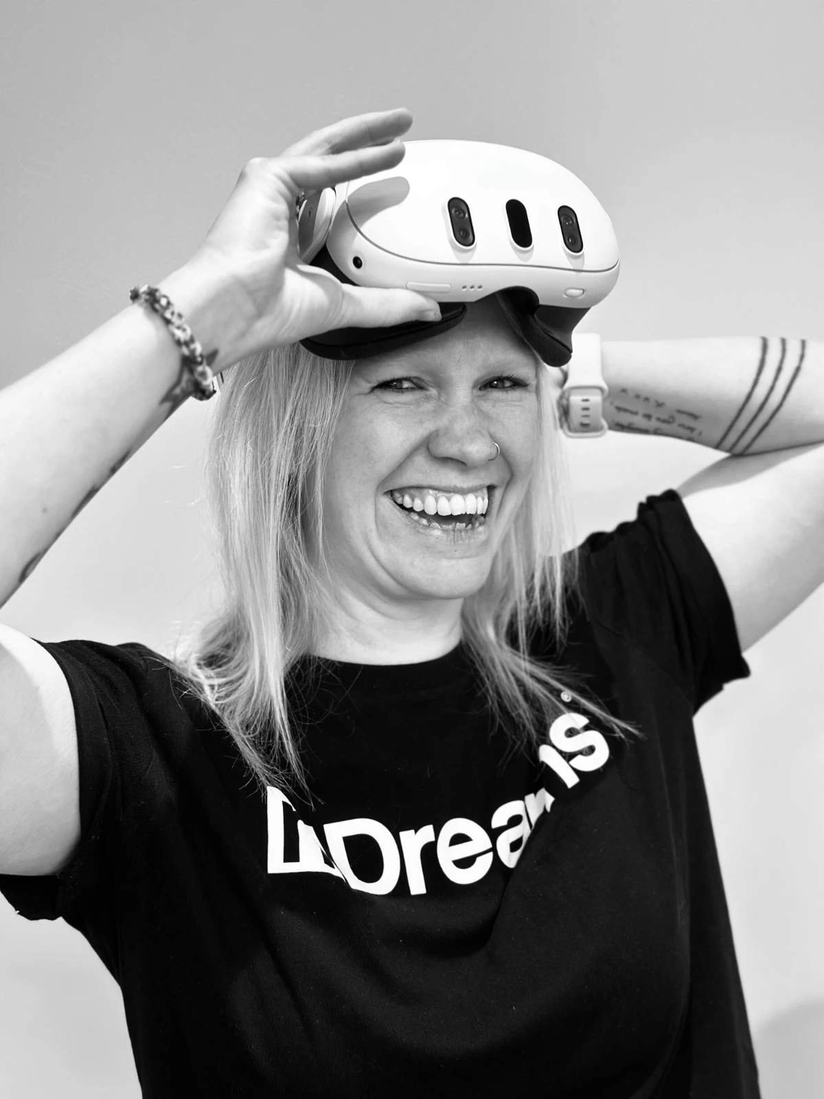 Ali Durrant smiling as she lifts a VR headset.